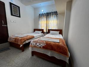 two beds in a room with a window at Hotel City Nibash in Dhaka