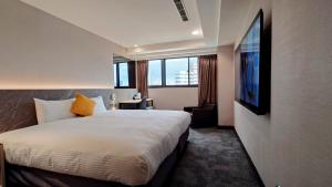 Una habitación de hotel con una cama y un televisor de pantalla plana. en Hub Hotel Taichung Wenxin, en Taichung