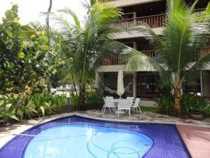 a pool in front of a hotel with a table and chairs at Nannai residence Flat 202 in Porto De Galinhas