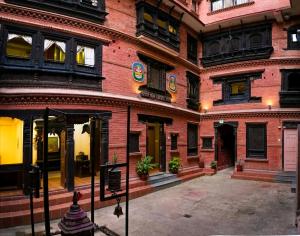 Tranquil Haven with shared kitchen access at greentara heritage home في باتان: مبنى من الطوب الأحمر به نوافذ وفناء