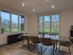 a dining room with a table and chairs and windows at Les champs dessus in Sarrey