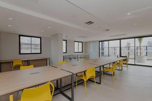 ein großer Konferenzraum mit einem langen Tisch und gelben Stühlen in der Unterkunft Essenza Elysia Premium Studio in Curitiba