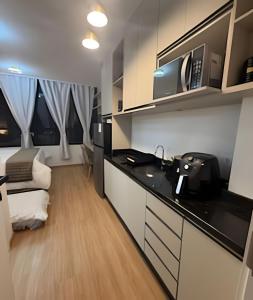 eine Küche mit Spüle und Mikrowelle in der Unterkunft Essenza Elysia Premium Studio in Curitiba