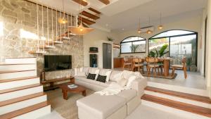 a living room with a white couch and a tv at Casa Amani 3BR Mediterranean w Pool Near Seminyak in Kerobokan