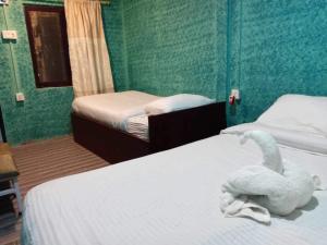 une chambre avec deux lits avec un cygne en peluche sur le lit dans l'établissement Rhino Spot Resort, à Meghauli
