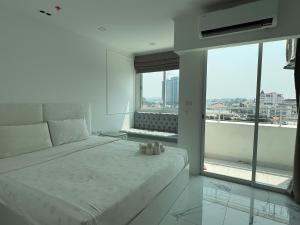 Sky Pool Apartment Hotel Near the Beach في جومتين بيتش: غرفة نوم بيضاء مع سرير ونافذة كبيرة