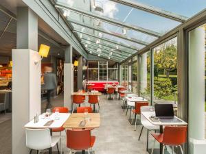 um restaurante com mesas, cadeiras e janelas em ibis Paris Meudon Velizy em Meudon