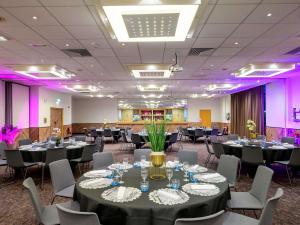 Una sala de conferencias con mesas y sillas e iluminación violeta. en Novotel Birmingham Centre, en Birmingham