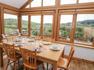 uma sala de jantar com mesa, cadeiras e janelas em Lough Cluhir Cottage em Myross