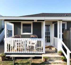 een klein huis met een veranda met twee stoelen bij Egret in Holden Beach +7 foto's