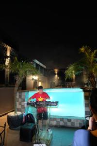 um homem parado em frente a uma piscina à noite em Le Chanvre Hanoi Hotel & Spa em Hanói