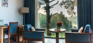 a room with a table and chairs and a large window at Mountain Retreat Kodai in Kodaikānāl