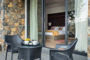a patio with two chairs and a table with a bed at Mountain Retreat Kodai in Kodaikānāl