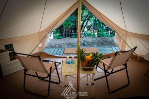 The River Glampstay في Ấp Long Ðại: خيمة فيها كرسيين وطاولة فيها