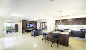 a kitchen and living room with a counter and chairs at Popular Grand Villa Shepparton in Shepparton
