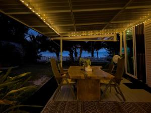 una mesa de madera y sillas en un patio con luces en Three Palms - Beach Front Tiny House by SP Villa, en Nathon Bay