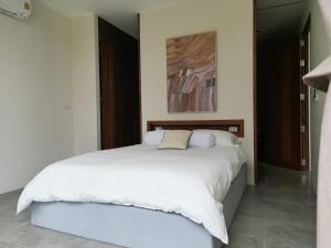 een slaapkamer met een wit bed en een schilderij bij Villa Noor by S&P Villa Management in Ko Phangan +42 foto's