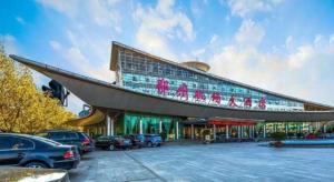 a large building with cars parked in a parking lot at Zhengzhou Airport Hotel in Zhengzhou Xinzheng International AIrport