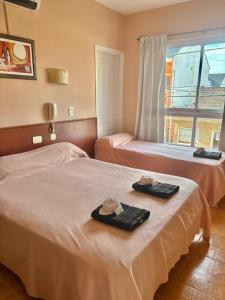 Dos camas en una habitación con sombreros y toallas. en NEW Hotel Playa, en Santa Teresita