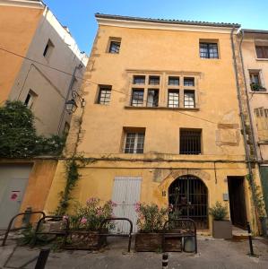 Un edificio amarillo con ventanas y flores delante. en Exceptional apartment, en Aix-en-Provence
