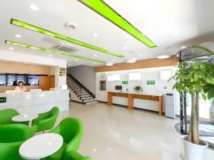 Vatica JiangsuJianguo Road Xuanwu Market Hotel في سوزهو: لوبي مكتب فيه كراسي خضراء وامرأه
