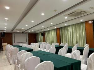 Vatica JiangsuJianguo Road Xuanwu Market Hotel في سوزهو: قاعة اجتماعات بها طاولات خضراء وكراسي بيضاء