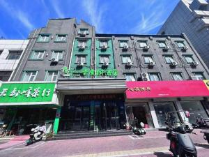 Vatica JiangsuJianguo Road Xuanwu Market Hotel في سوزهو: مبنى كبير على شارع المدينة وبه مباني