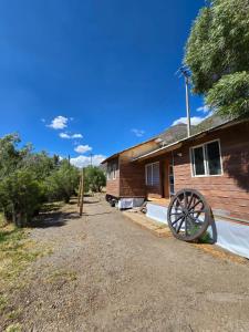 una casa in legno con una ruota davanti di Cabaña Valle del Yeso a El Manzanito