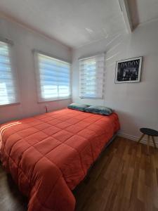 una camera da letto con un grande letto rosso con due finestre di Cabaña Valle del Yeso a El Manzanito