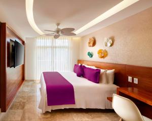 um quarto com uma cama grande e almofadas roxas em Senses Quinta Avenida Hotel By Artisan em Playa del Carmen