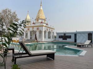 a building with a swimming pool and a building with a temple at Parth King Resort Tarapith A Unit of Prattay Infratech Private Limited in Tarapith