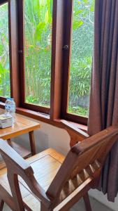 una silla de madera sentada frente a una ventana en Kosasih 1919 A Dutch-Retro House, en Banyuwangi
