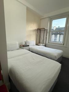 three beds in a hotel room with a window at Swanvale Lodge Hotel in Great Yarmouth