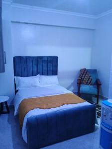 MeruZayana staycation的一间卧室配有一张带蓝色床头板和椅子的床