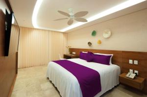 a bedroom with a large bed with purple pillows at Senses Quinta Avenida Hotel By Artisan in Playa del Carmen