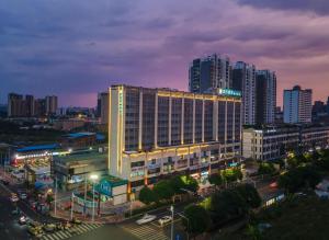 City Comfort Inn Nanning Xingning District Government Maternal and Child Health Hospital في نانينغ: مبنى مضاء في مدينة في الليل