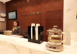 City Comfort Inn Wuhan Zhongnan Road Metro Exit في ووهان: امرأة تجلس على المنضدة مع الخلاط