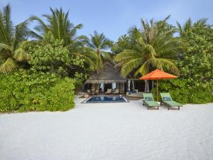 a resort with a pool and two chairs and an umbrella at Taj Exotica Resort & Spa, Maldives in South Male Atoll