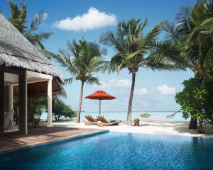 a swimming pool next to a beach with palm trees at Taj Exotica Resort & Spa, Maldives in South Male Atoll