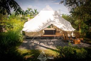 The River Glampstay في Ấp Long Ðại: خيمة فيها سرير وكراسي في ساحة