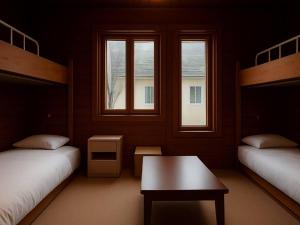 八幡平市安比高原ロッジタンデム的客房设有两张床、一张桌子和两个窗户。