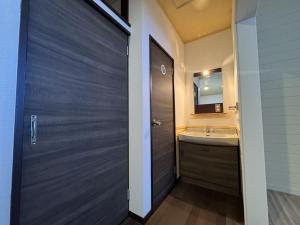 a bathroom with a wooden door and a sink at 安比高原ロッジタンデム in Wada