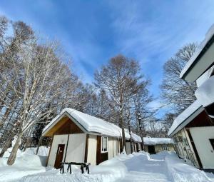 a house covered in snow in front of trees at 安比高原ロッジタンデム in Wada +7 photos