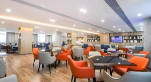 City Comfort Inn Wuhan Tianhe Airport Outlets في ووهان: مطعم فيه كراسي وطاولات برتقالية وبيضاء