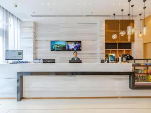 City Comfort Inn Chengdu Southwest University of Finance and Economics Wansheng Metro Station في تشنغدو: وجود امرأة جالسة في مكتب الاستقبال في بهو الفندق