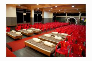 Una habitación llena de sillas rojas, mesas y sillas. en Kamala Shanti Palace, en Solapur