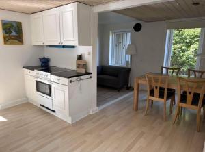 TommerupにあるThe Coziest Farm Holiday In The Countrysideの白いキャビネットとテーブルのあるキッチンとダイニングルーム