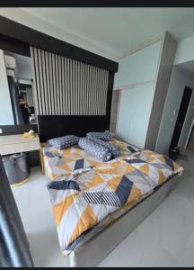 Delft Apartement Sunset CPI Makassar في Tanjungbunga: غرفة نوم بها سرير مع لحاف عليه