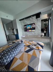 Delft Apartement Sunset CPI Makassar في Tanjungbunga: غرفة نوم مع سرير وتلفزيون بشاشة مسطحة