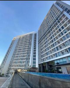 Delft Apartement Sunset CPI Makassar في Tanjungbunga: مبنى طويل به مسبح أمامه